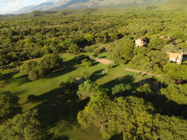 Vista aérea del parque de La Quinta Resort con canchas, cabañas y monte nativo en Merlo